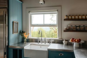Farmhouse sink with stainless steel countertops and blue cabinets.