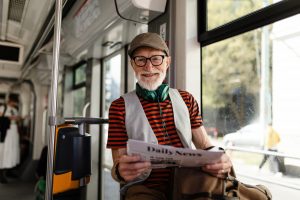Elderly man traveling through the city by bus, reading a